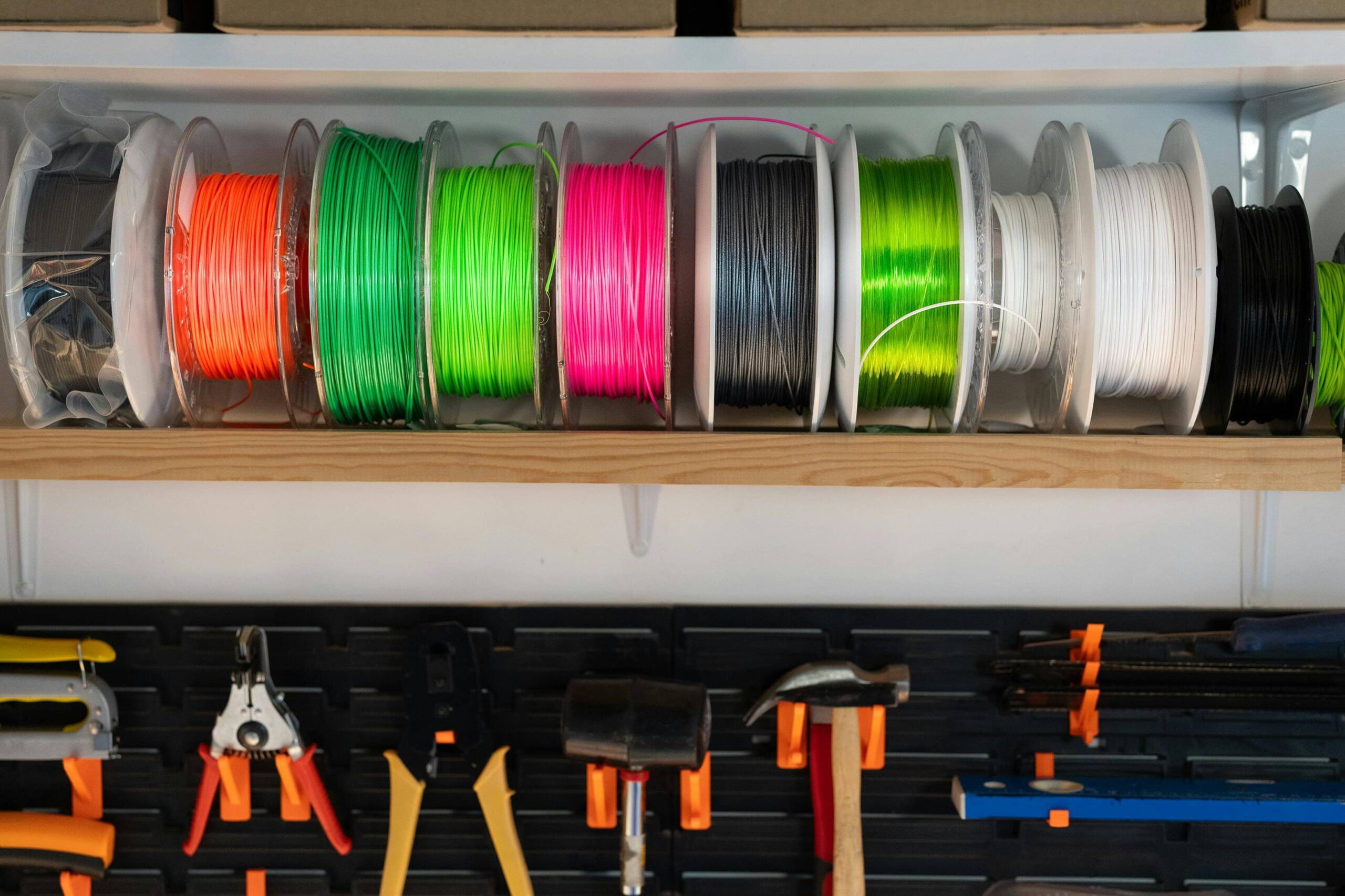 Different 3d print filament spools showcasing color variaty with a 3d printer working in background