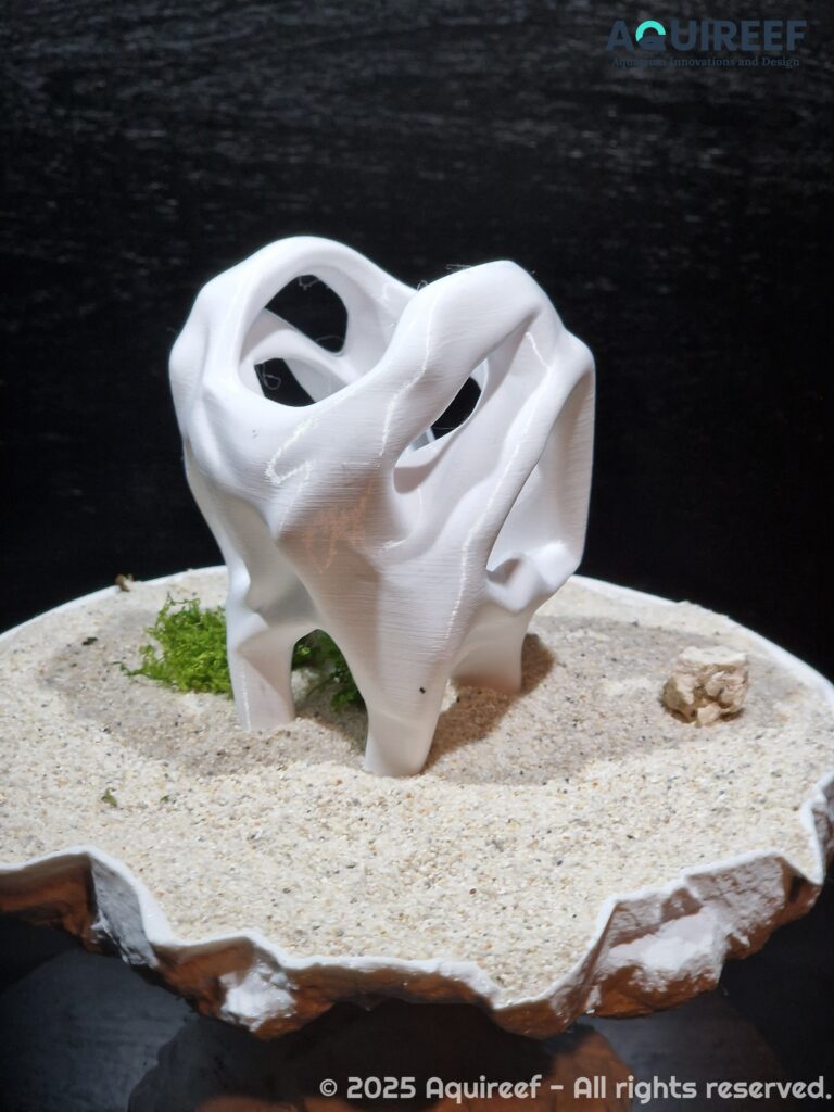 A back view of a cichlid unique design cave showcased on sand soil. Smooth edges safeguard the fish swimming through it. A design by AquireefęD