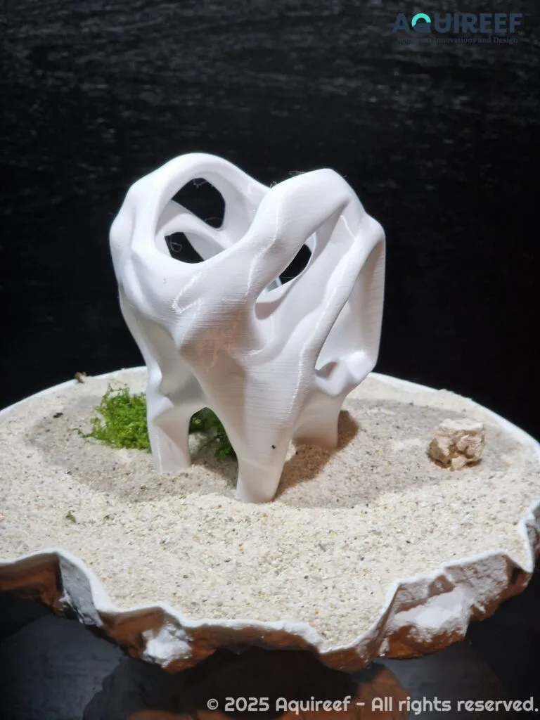 A back view of a cichlid unique design cave showcased on sand soil. Smooth edges safeguard the fish swimming through it. A design by AquireefęD